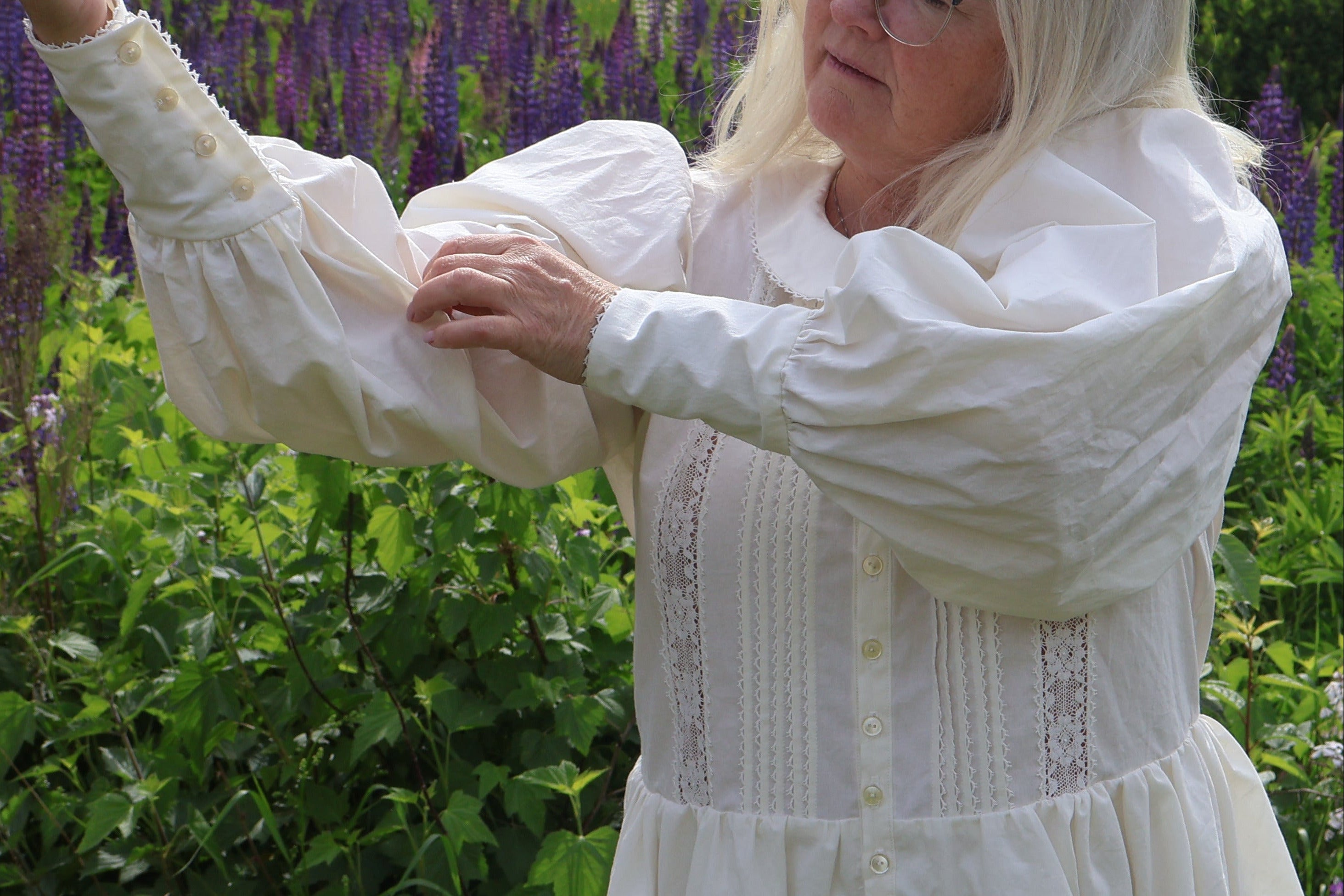 Woman in a white dress standing in a field of purple flowers